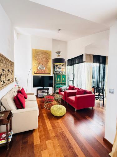 a living room with a white couch and red furniture at Ático en Plaza de la Constitución 3 bedrooms in Málaga