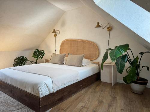 a bedroom with a large bed with two plants at Le Pré de la Mer Suite & SPA Privatif in Querqueville