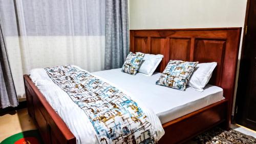 a bed with a wooden headboard and pillows on it at Makali Private Villa- 2En-Suite Bedrooms in Arusha