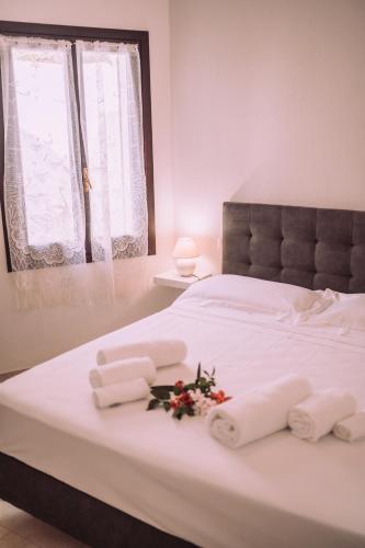 a white bed with towels and flowers on it at Appartamenti I Lentischi in Villasimius