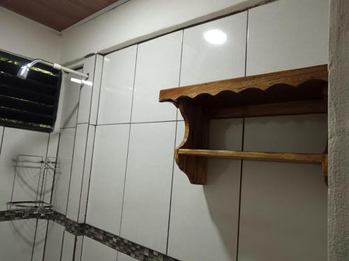 a bathroom with a white tiled wall with a wooden shelf at Señora Aura in Hone Creek
