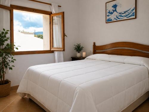 a bedroom with a white bed and a window at EL CHORRO Aire acondicionado Bar privado Barbacoa Amplios patios in Castalla