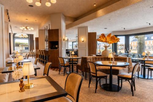 a restaurant with tables and chairs and windows at Hotel de Zon - Brasserie Bresson by Flow in Ommen