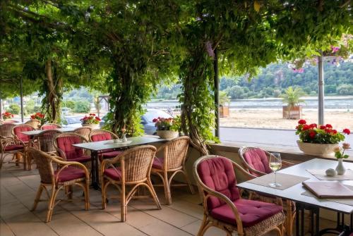 un ristorante con tavoli, sedie e alberi di Hotel Schön am Rhein a Rüdesheim am Rhein