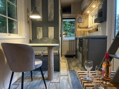 a kitchen with a table and two chairs and wine glasses at Lille Degnboel Tiny House in Hjørring