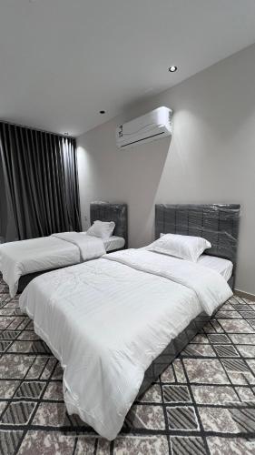 two beds in a room with white sheets at شالية بمسبح وجلسة خارجية- غرفتين نوم وملحق خارجي ومدخل سيارة in Unayzah