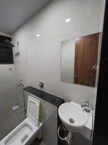 a bathroom with a sink and a toilet and a mirror at NilayInn in Pandharpur