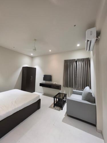 a white bedroom with a bed and a couch at NilayInn in Pandharpur