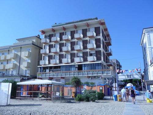 - un bâtiment sur la plage avec des personnes se déplaçant devant dans l'établissement Hotel Suprem, à Rimini