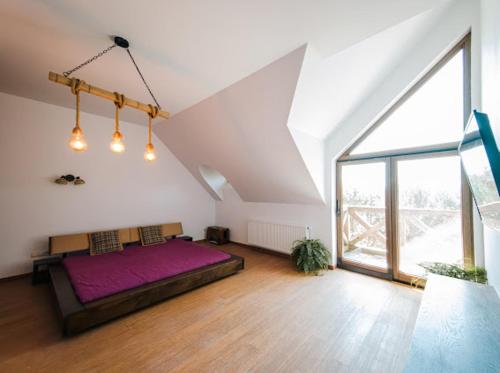 a bedroom with a large purple bed in a attic at Dom pod strzechą in Swornegacie