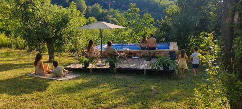 a group of people sitting in the grass at Konak ispod Subjela in Ševrljuge