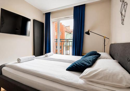 a bedroom with a large bed with a window at CudNajem Old Town Apartments - Bulvar in Elblag