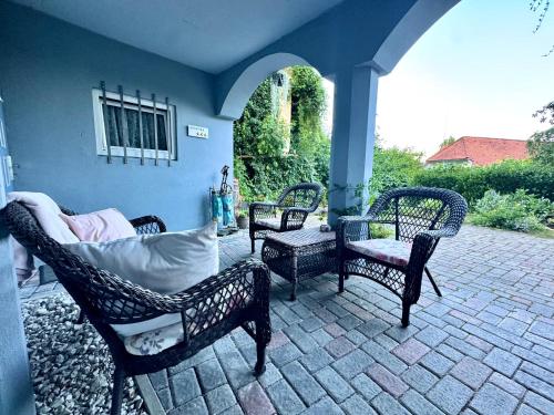 a patio with three wicker chairs and a table at Vila Kralj in Podčetrtek