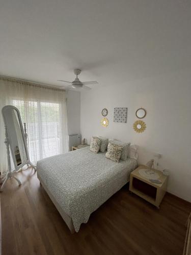 a white bedroom with a bed and a table at Apartamento Terraza Mar El Azul in Santa Susanna