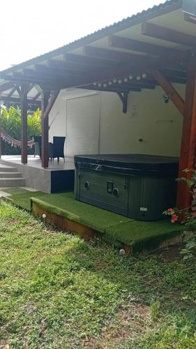 a patio with a table and a chair under a roof at Maison cosy à Lamentin, 20m², climatisation in Lamentin