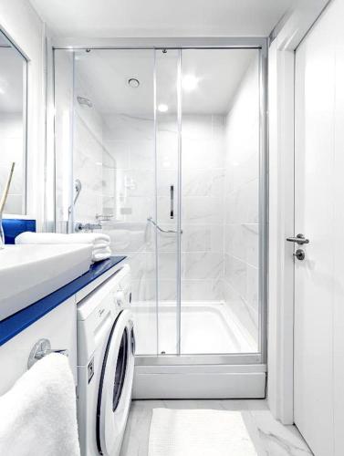 a white bathroom with a shower and a washing machine at Orbi City Sea View Balcony ApartHotel in Batumi