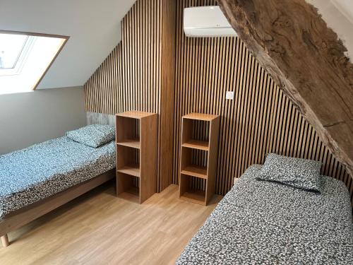 a bedroom with two beds and a wooden wall at Les maisons de Palis in Salvagnac-Cajarc