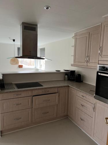 a kitchen with wooden cabinets and a stove top oven at Hus i to plan i Nakskov by in Nakskov