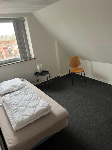 a bedroom with a bed and a chair and a window at Hus i to plan i Nakskov by in Nakskov