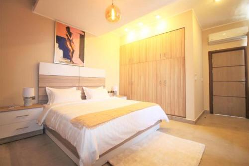 ein Schlafzimmer mit einem großen Bett und einem Kleiderschrank in der Unterkunft Cross Suites in Tema