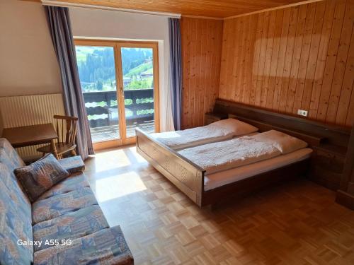 a bedroom with a bed and a couch and a window at Haus Mooswald in Lechleiten