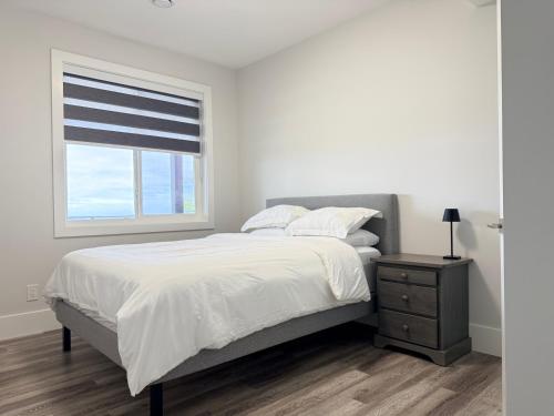 ein weißes Schlafzimmer mit einem großen Bett und einem Fenster in der Unterkunft Ocean Whispers in Nanaimo