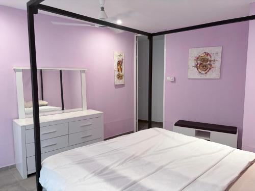 a bedroom with purple walls and a bed and a mirror at Mais Residence in Bijilo