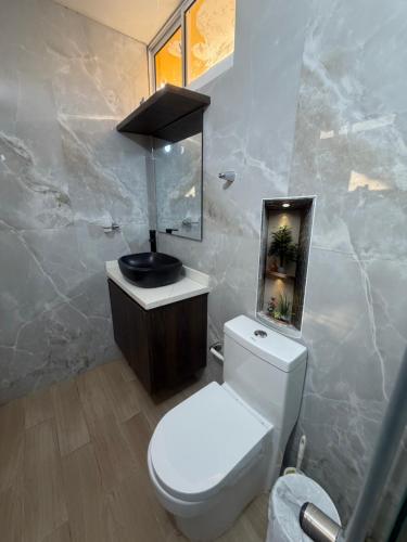 a bathroom with a white toilet and a sink at Cabaña Sueños del Mar in Santa Marta