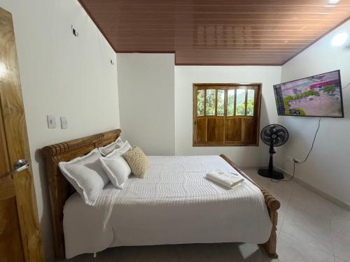 a bedroom with a bed with white sheets and a window at Cabaña Sueños del Mar in Santa Marta