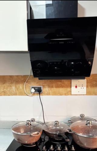 three bowls on top of a stove with a microwave at M & A Homes Ilorin in Ilorin