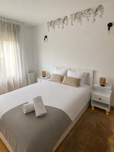 a bedroom with a large white bed with a branch on the wall at El Pasaje del Marqués in El Burgo de Osma