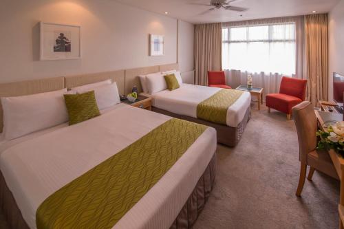 a hotel room with two beds and a desk at Sudima Hotel Lake Rotorua in Rotorua