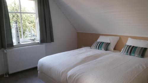 a bedroom with a white bed and a window at Ditzumerhuuske in Ditzum