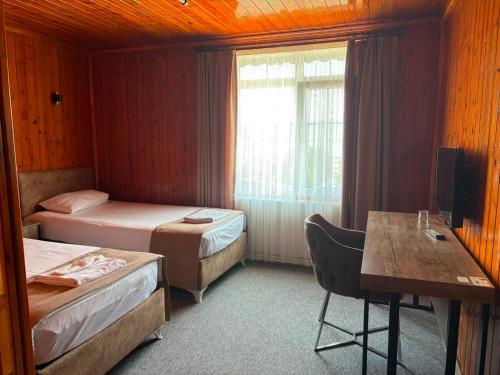 a room with two beds and a desk and a table at Gölpark Otel in Yeniçağa