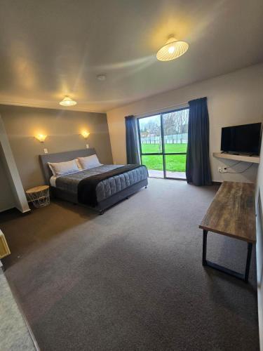 a bedroom with a bed and a large window at Raceway Lodge in Feilding