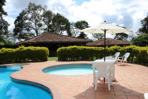 a patio with an umbrella and chairs next to a pool at Finca Hotel Cabaña Fercho in Quimbaya