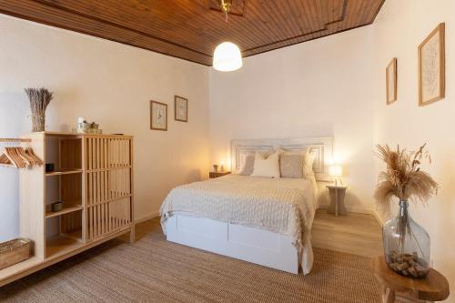 a bedroom with a white bed and a wooden ceiling at A casa da avó Tina in Montemor-o-Novo