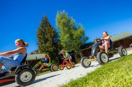 a group of people riding on toy cars on a road at Queenstown Top 10 Holiday Park in Queenstown