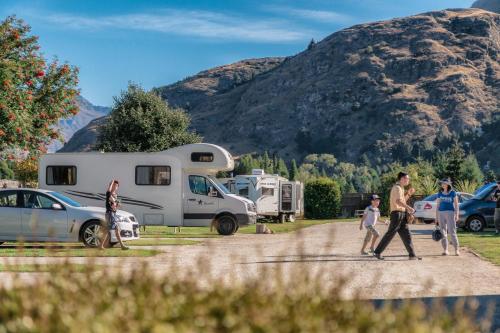 a group of people walking down a dirt road with a trailer at Queenstown Top 10 Holiday Park in Queenstown