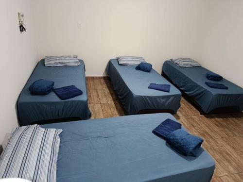 three beds in a room with blue sheets at Pousada Paraíso in Telêmaco Borba