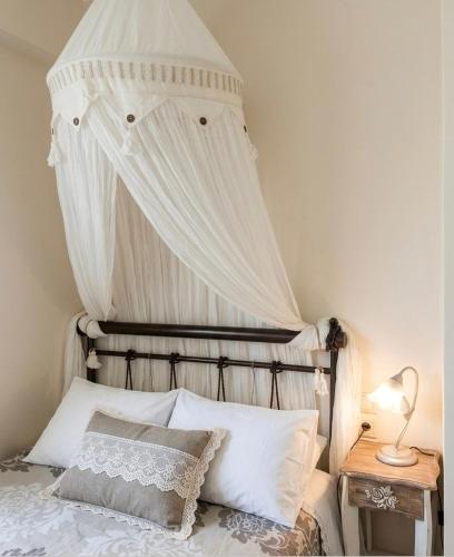 a canopy over a bed with white sheets and pillows at Dreamcatcher Maisonette No.2 in Kalavrita