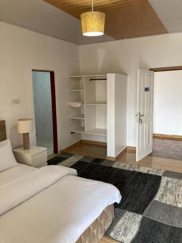 a bedroom with a white bed and a closet at Rashlie apartment in Freetown