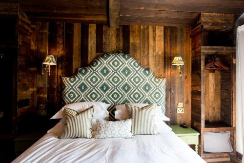 a bedroom with a white bed with a wooden wall at Oak - The Nook Lodges in Wrenbury