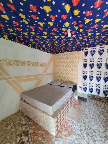 a bedroom with a bed with a colorful ceiling at SEN-CASA- TOURiSME in Kabadio