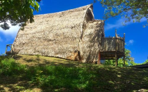 a large thatched building on top of a grassy hill at Oneta Resort in Ono Island
