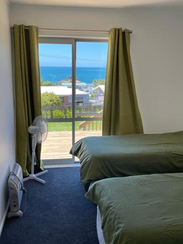 a bedroom with two beds and a window with the ocean at Black Box Bach in Coopers Beach