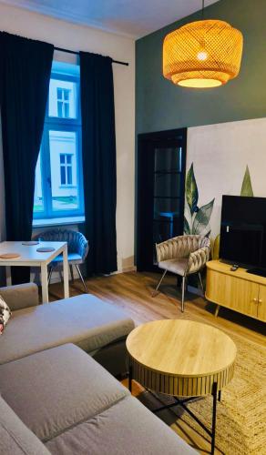 a living room with couches and a table and a tv at BOOGIE Home Nawrot 13 in Łódź