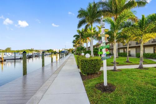 a sidewalk next to a canal with palm trees and a street sign at Studio, kitchenette, pool & Tiki Bar in Sarasota