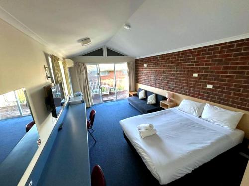a hotel room with a bed and a brick wall at Merimbula Coastline Motel in Merimbula