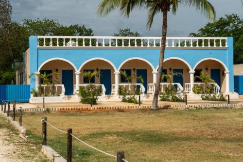 a blue building with a palm tree in front of it at Hotel Hacienda IMI 3 in Imí